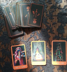 3 tarot cards on a table next to deck