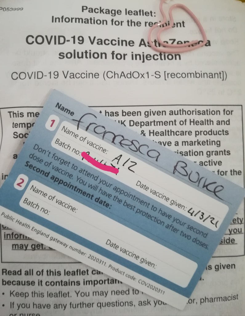 photograph of Covid AstraZeneca vaccine card on top of package leaflet information