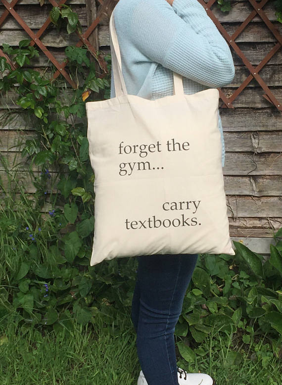 person modelling tote bag reading 'forget the gym... carry textbooks.'