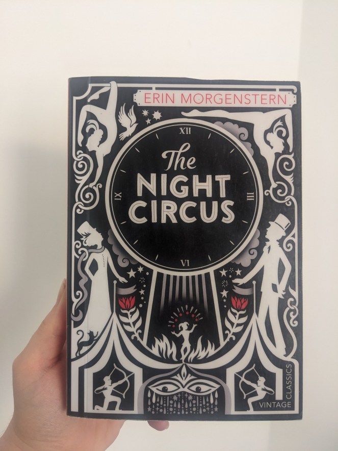 hand holding paperback copy of The Night Circus by Erin Morgenstern