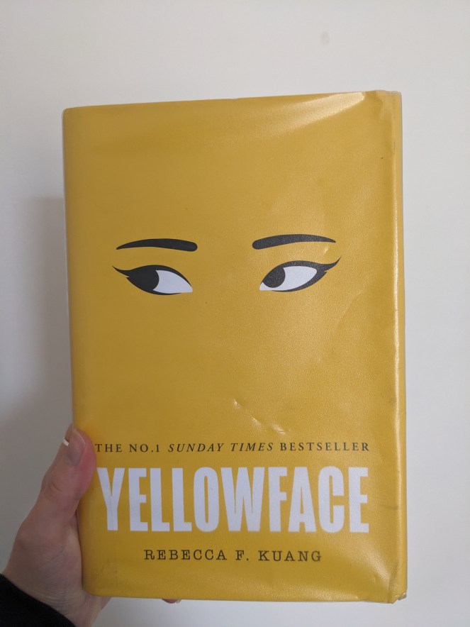 hand holding hardback cover of Yellowface by RF Kuang